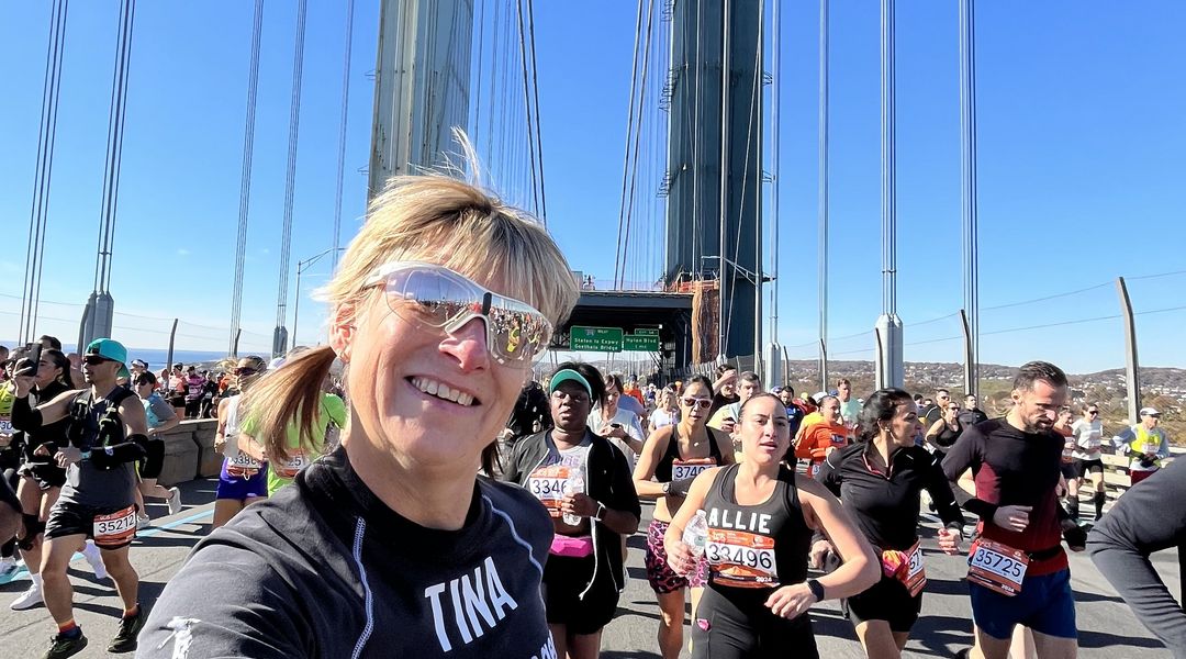 Eine Frau in Jogginganzug läuft auf einer Brücke und hält eine Medaille beim laufen