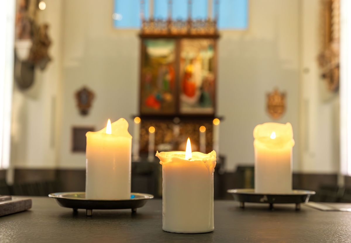 zur Vergrößerungsansicht des Bildes: Farbfoto: drei brennende Kerzen auf einem Altar