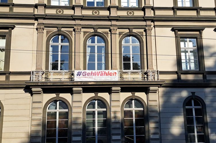 Zu sehen ist das Banner mit der Aufschrift "gehwählen" am Balkon des Rektoratsgebäudes in der Goethestraße