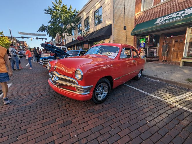 Farbfoto: Aufnahme eines geparkten roten Autos in einer belebten Straße