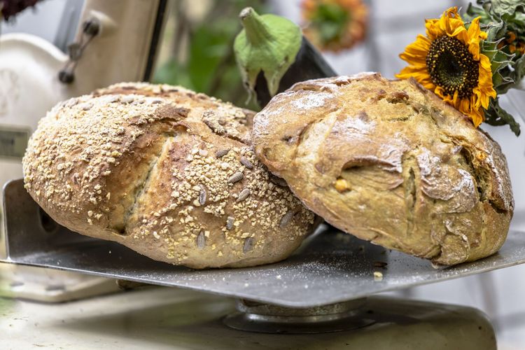 Farbfoto: Detailaufnahme von zwei Körnerbrötchen, die auf einer rustikalen Waage liegen.