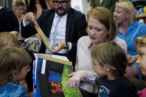 Auf dem Bild schauen sich Bundesfamilienministerin Lisa Paus und Sachsens Kultusminister Christian Piwarz - umringt von Kindern - Bilder der Kleinen an.