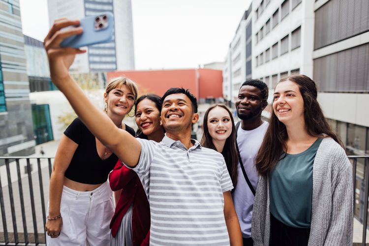 Colour photo: 6 people take a selfie in front of the inner courtyard of Leipzig University