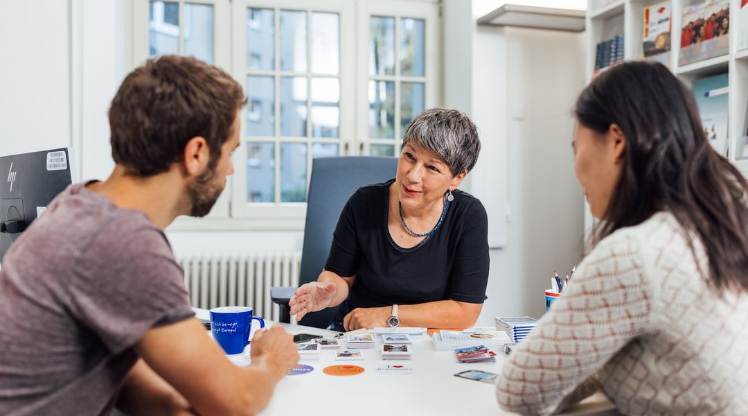 Zwei Menschen sitzen zum Beratungsgespräch mit einer Mitarbeiterin der Stabsstelle Internationales an einem Schreibtisch