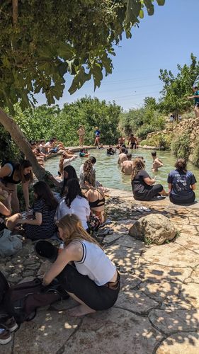 Bild einer Quelle in Jerusalem, in der viele Menschen bei sonnigem Wetter baden.