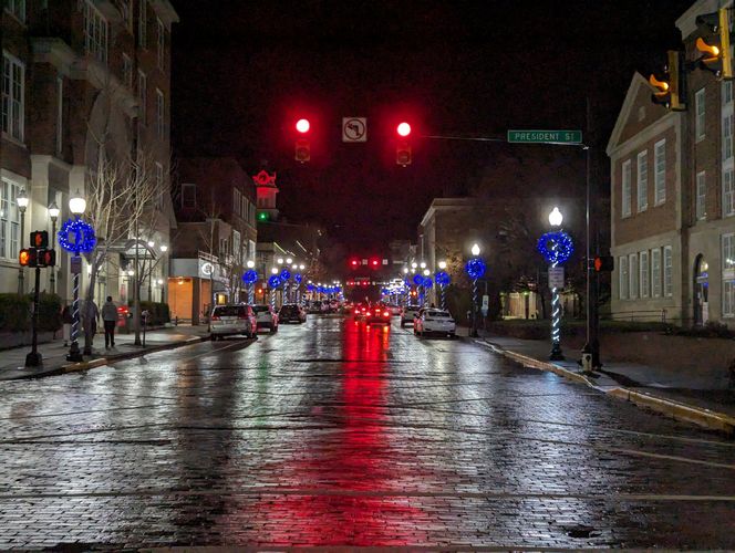 Farbfoto: Aufnahme einer Straße bei Nacht mit roten Ampeln und blauen Straßenlaternen