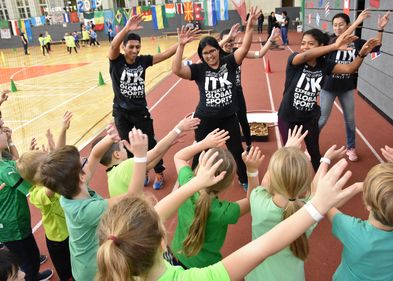 Das Bild zeigt ITK-Trainer:innen bei einem Sportfest mit Kindern in einer Sporthalle. 