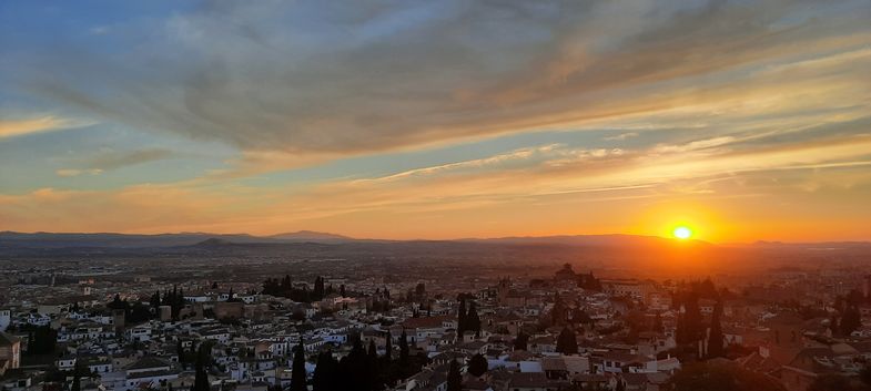 Blick über die Dächer Granadas mit Sonnenuntergang im Hintergrund