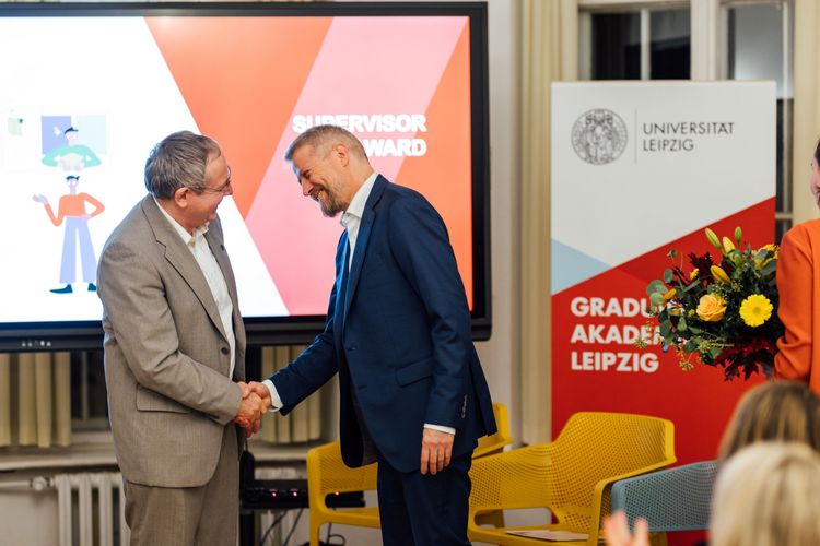 Prof. Gläser gratuliert Prof. Kohlmann, ein Blumenstrauß wird gereicht