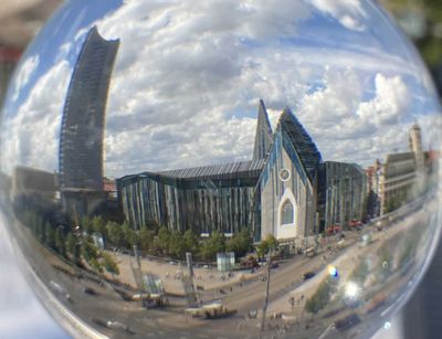 Farbfoto: Blick auf eine Glaskugel, in der sich das Hauptgebäude der Universität Leipzig spiegelt.