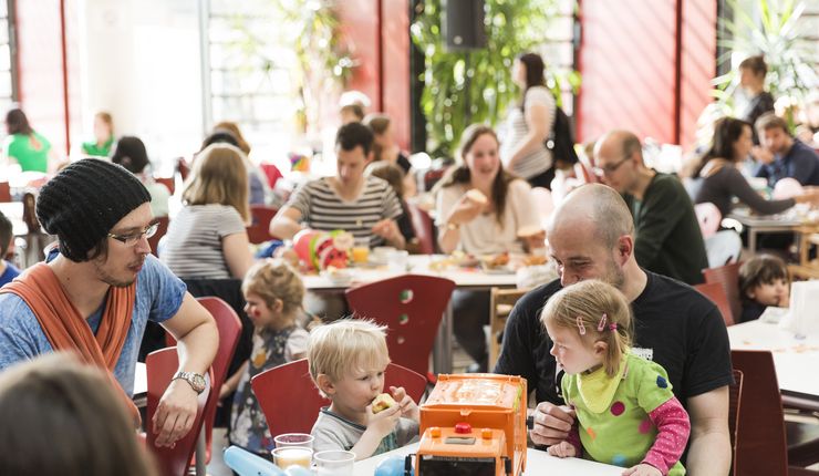 Foto: Eltern, die mit ihren Kindern beim Frühstück in der Mensa sitzen