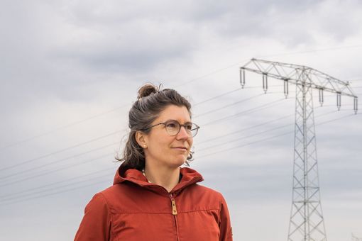 Daniela Russ vor einem Feld mit Windrad und Strommast